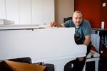 Jean-Luc Gassmann sitzt vor einem weissen Klavier und und blickt neben der Kamera vorbei. 