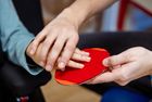 Zwei Hände halten gemeinsam eine rote, kreisrunde Karte.