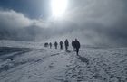 Die Oberstufe wandert durch den Schnee. Es hat ein Gemisch von Wolken und Sonne. Die Sonne kann sich knapp durchsetzen. 